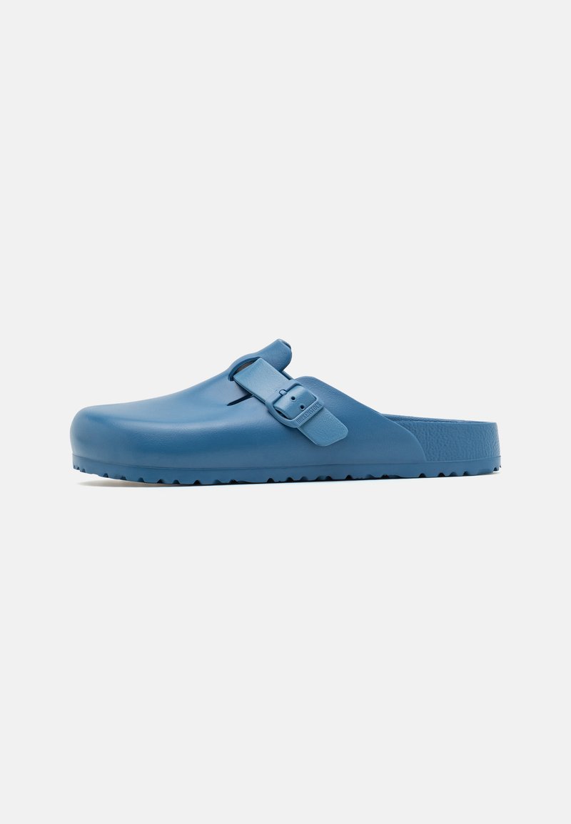 Zuecos de goma azules con punta redondeada, correa ajustable y suela texturizada. Acabado liso sin patrones ni acentos visibles.