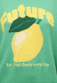 Illustration d'un citron jaune avec une feuille verte et le texte « Future » au-dessus et « Mangez des fruits frais chaque jour » en dessous sur un tissu vert.