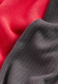 Strickstoff in Rot und Dunkelgrau mit einer weichen, strukturierten Haptik. Die Materialien zeigen eine glatte Oberfläche mit feinen Rippungen.