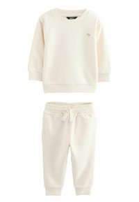 Helles beige Sweatshirt mit geripptem Halsausschnitt und Bündchen, kombiniert mit passenden Jogginghosen, die einen elastischen Bund und zwei Seitentaschen haben.