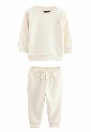 Light beige sweat top with ribbed neckline and cuffs, paired with matching sweatpants featuring an elastic waistband and two side pockets.