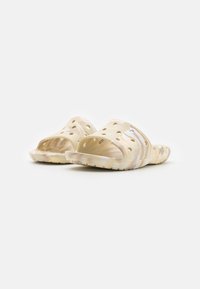 Infradito di colore beige chiaro con un design testurizzato e perforato. Realizzati in materiale flessibile e dotati di una suola sagomata per il comfort.