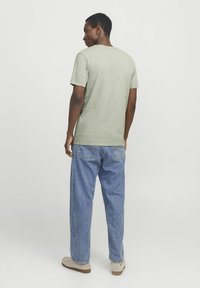 Lys grøn bomulds T-shirt med korte ærmer, parret med blå denim jeans. Casual fit, med rund halsudskæring og bagansigt.