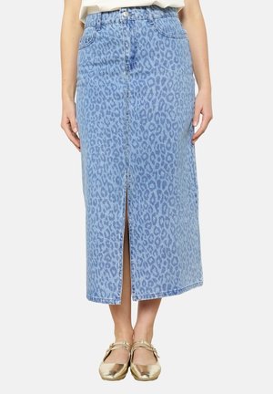 Jupe midi en jean bleu avec un motif léopard discret, fente devant, portée avec des chaussures dorées style Mary Jane.