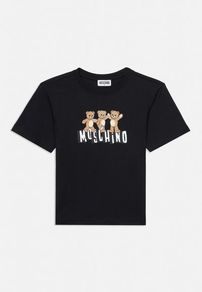 T-shirt noir à manches courtes avec trois ours en peluche malicieux au-dessus du mot « MOSCHINO » en lettres blanches épaisses sur le devant.