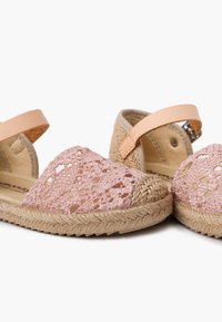 Roosa heegeldatud espadrillide sandaalid beežide nahkraamidega, millel on punutud jootsest tallad ning avatud varvaste disain koos dekoratiivsete lõikeaukudega.