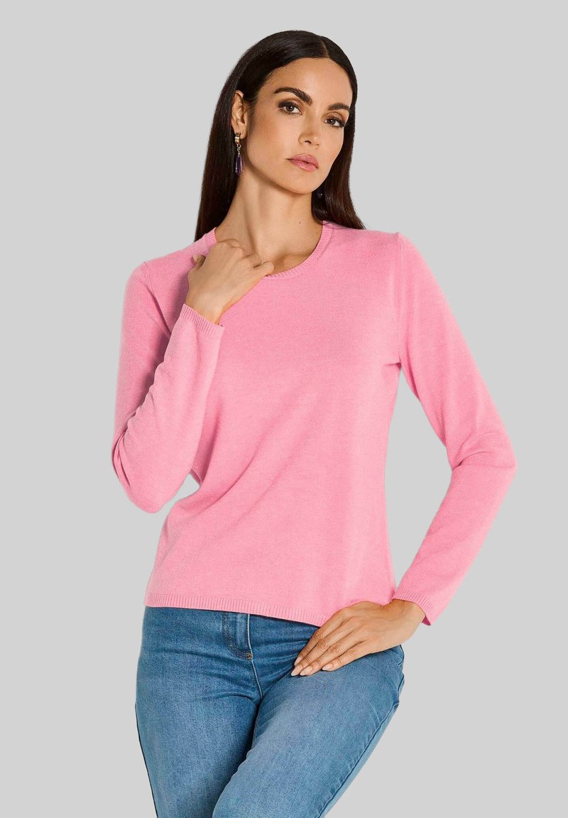 Rosa Langarmpullover mit rundem Halsausschnitt und gerippten Bündchen, kombiniert mit blauen Jeans. Weiche Textur und lockere Passform.
