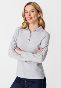 Grijze lange mouwen polo shirt met een kraag, voorzien van een knopenlijst, zijsplitten en een zachte textuur. Casual gedragen over denim.