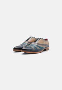 Scarpe eleganti stringate che presentano un design bicolore con pelle beige e blu scuro, punta lucida, tacco in legno e strisce a contrasto.
