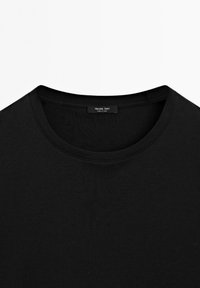 T-shirt noir à col rond avec coutures visibles et une petite étiquette de marque à l’intérieur du col indiquant "Massimo Dutti."