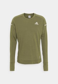 Oliivinvihreä pitkähihainen urheiluipaita, joka on valmistettu karheasta kankaasta. Paidassa on pyöreä kaula-aukko ja valkoinen Adidas-logo rinnassa.