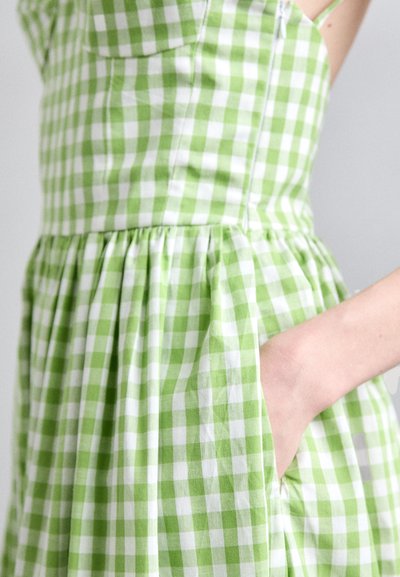 Groene en witte gingham jurk met een aansluitende top, geplooide rok en zijzakdetails. Gemaakt van een gestructureerde katoen stof.