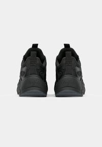 Svarta sportskor med en texturerad tygövre, vadderad krage och logotypdetalj på hälen. Yttersula med ett mönstrat mönster för bra grepp.