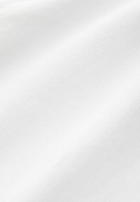 Textile blanc avec une surface lisse, légèrement texturée, présentant un fin côtes diagonales à travers le tissu. Pas de motifs ni d'accents.