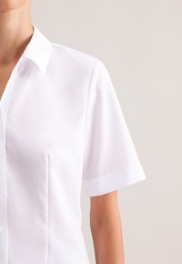 Weißes Kurzarmhemd mit spitzem Kragen, durchgehender Knopfleiste, glatter Textur und zwei vertikalen Abnähern auf der linken Seite.