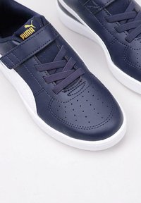 Sneakers blu navy con una tomaia in pelle liscia, accenti bianchi e dettagli perforati. Presentano lacci e una cintura in velcro per la chiusura.