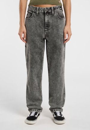Grå syre-vasket denim bukser med løs pasform, høj talje og fem lommer. Sorte syninger og opsmøgede ærmer. Parret med sorte sneakers.