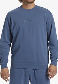 Felpa blu in misto cotone, con collo a giro, polsini e orlo a costine, e logo ricamato sul petto. Texture liscia.