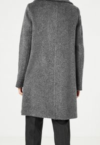 Grijze jas van wolmix met een gestructureerde afwerking, halflange snit, brede kraag en lange mouwen. Heeft een achternaad en een zachte uitstraling.