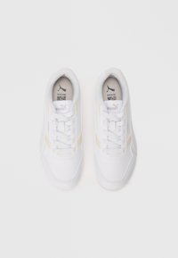 Pair of white Puma sneakers with beige stripes, laced up, viewed from above on a plain white background.