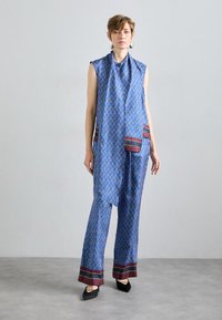 Sinine mustriga riietus, millel on varrukateta topp ja laiad püksid, millel on marooni aktsendid ja sile tekstuur.