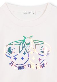 Witte shirt met een glanzend, holografisch motief van een mot met halve manen en sterren, met de tekst "The Way You Shine."