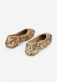 Bailarinas doradas con lentejuelas, de punta redondeada, parte superior de tela suave y suela de goma plana. Los zapatos presentan lentejuelas multicolores que brillan en toda su superficie.