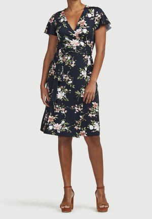 Laivastonsininen kukkakuvioinen kietaisumekko, jossa on lyhyet liehuvat hihat, syvä V-pääntie, vyötärö kapeana ja polven pituinen helma. Koristeltu vaaleanpunaisilla ja valkoisilla kukilla.