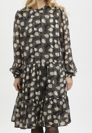 Robe noire avec un léger motif de feuilles, manches longues, ourlet froncé et tissu transparent. Les détails plissés et les poignets élastiqués ajoutent de la texture.