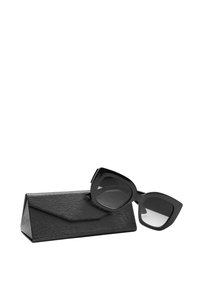Occhiali da sole neri con montatura geometrica appoggiati su un astuccio nero texturizzato. Le lenti sono leggermente colorate e con una sfumatura.
