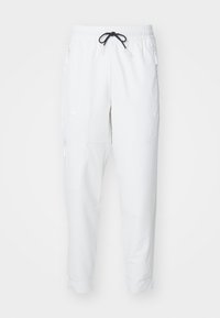 Witte sportbroek met een elastische tailleband, zwarte trekkoord, ritszakken en taps toelopende benen. Gemaakt van lichte, gladde stof.