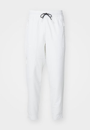 Pantaloni sportivi bianchi con cintura elastica, cordino nero, tasche con zip e gambe svasate. Realizzati in tessuto leggero e morbido.