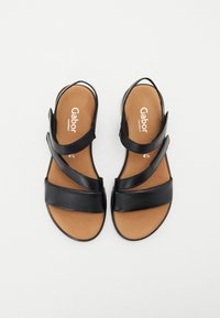 Black leather sandals with crossed straps, open back, and contoured brown insole. Features Gabor branding and a flat sole.