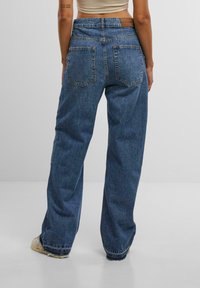 High-waisted, loose-fitting blue denim jeans with a faded finish, two back pockets, and frayed hems. Made of sturdy denim material.