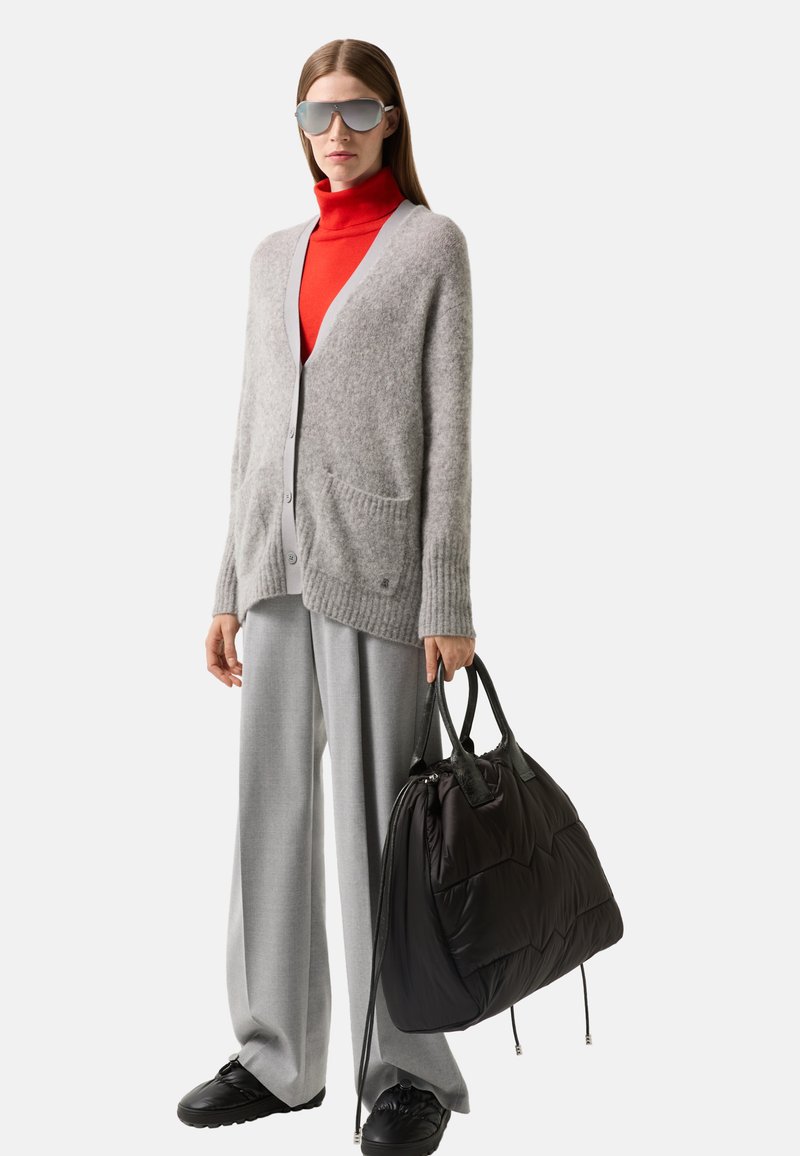 Grauer Wollcardigan mit geripptem Saum, rotem Rollkragenpullover, hellgrauen, weiten Hosen und einer schwarzen, gesteppten Umhängetasche mit strukturierten Akzenten.