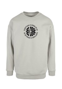 Light grey sweatshirt made of soft fabric. Features a round black graphic pattern with the text "Everything is gonna be OK" in bold font.