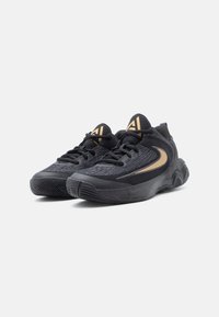 Čierne športové topánky s textúrovaným zvrškom, so zlatými akcentmi a výrazným dizajnom swoosh. Hrubá gumová podrážka pre trakciu.