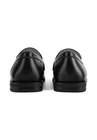 Chaussures en cuir noir au texture lisse, talon bas et arrière rond. Le design présente des coutures subtiles et une finition mate.
