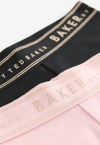 Dwie pary damskiej bielizny są w kolorze czarnym i różowym. Każda z nich ma materiałowy pas z nazwą marki "TED BAKER" napisaną złotymi literami.