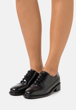 Chaussures habillées en cuir noir avec une finition brillante, bout rond, talon bas et design à lacets. Texture lisse avec des accents contrastés.