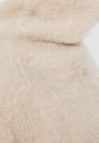 Tissu beige doux et duveteux avec une texture duveteuse, légèrement plié pour mettre en valeur son épaisseur et sa douceur.