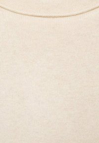 Cremfarbener Strickstoff, der ein feines, strukturiertes Muster mit leichtem Stretch zeigt; verfügt über einen runden Ausschnitt und minimale Details.