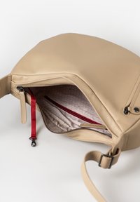 Beige Ledertasche mit glatter Oberfläche, ausgestattet mit einem Reißverschluss und einer roten Innentasche. Schlichtes, funktionales Design.