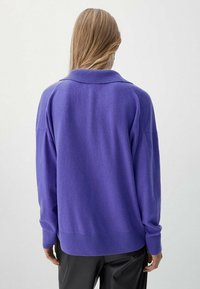 Lila übergroßer Pullover mit Kragen, gerippten Manschetten und Saum, aus weichem Material, von hinten gezeigt.