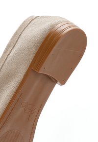 Scarpa in suede beige con suola in gomma tan e curvata. La suola ha un lieve tacco e dettagli di cucitura visibili lungo il bordo.