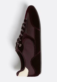 Baskets de sport bordeaux en velours et matériau lisse, avec un laçage texturé et un accent crème au niveau du talon. Bout arrondi et semelle plate.