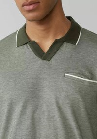 Graues Polohemd mit V-Ausschnitt, dunklem grünen Kragen und weißem Saum, ausgestattet mit einer kleinen Brusttasche und einem kontrastierenden Kantenverlauf.