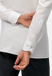 Witte langetermijn shirt met een textuurafwerking. Kenmerkt zich door een knopenmanchet met twee knopen en een strakke, getailleerde pasvorm.