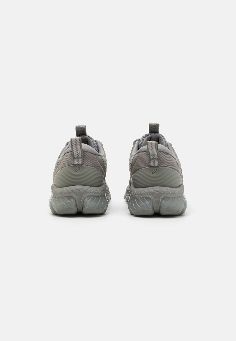 Graue Sportschuhe mit einem strukturierten Mesh-Obermaterial, gepolstertem Kragen und einer kontrastierenden, transparenten Gummisohle. Fersenlasche für einfaches Anziehen.
