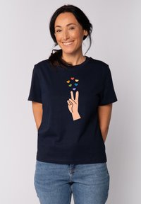Marineblauw katoenen T-shirt met een graphic van een hand die een vredesteken maakt, omringd door kleurrijke hartvormen in verschillende maten.
